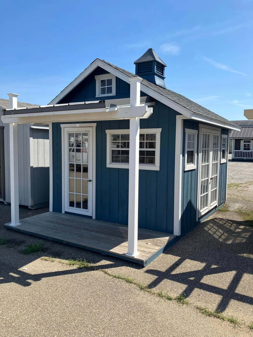 A blue shed with a cupola and porch