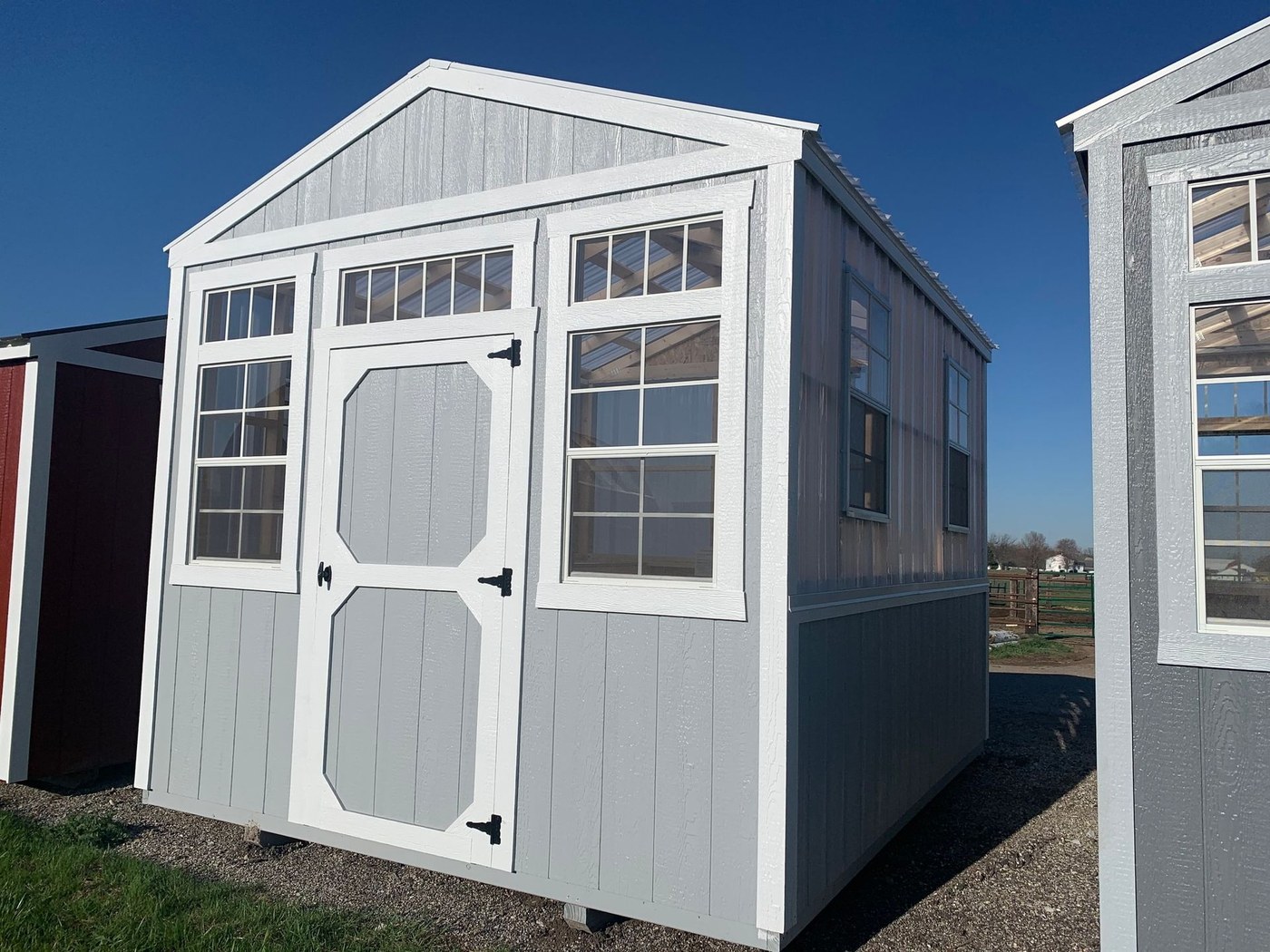A gray utility shed with transom windows