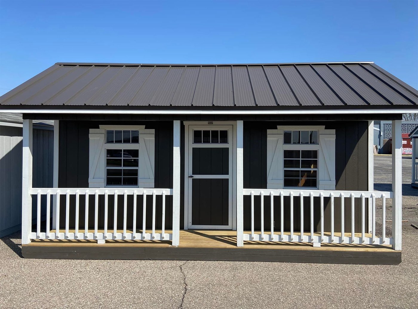 A black cabin with a white porch rail