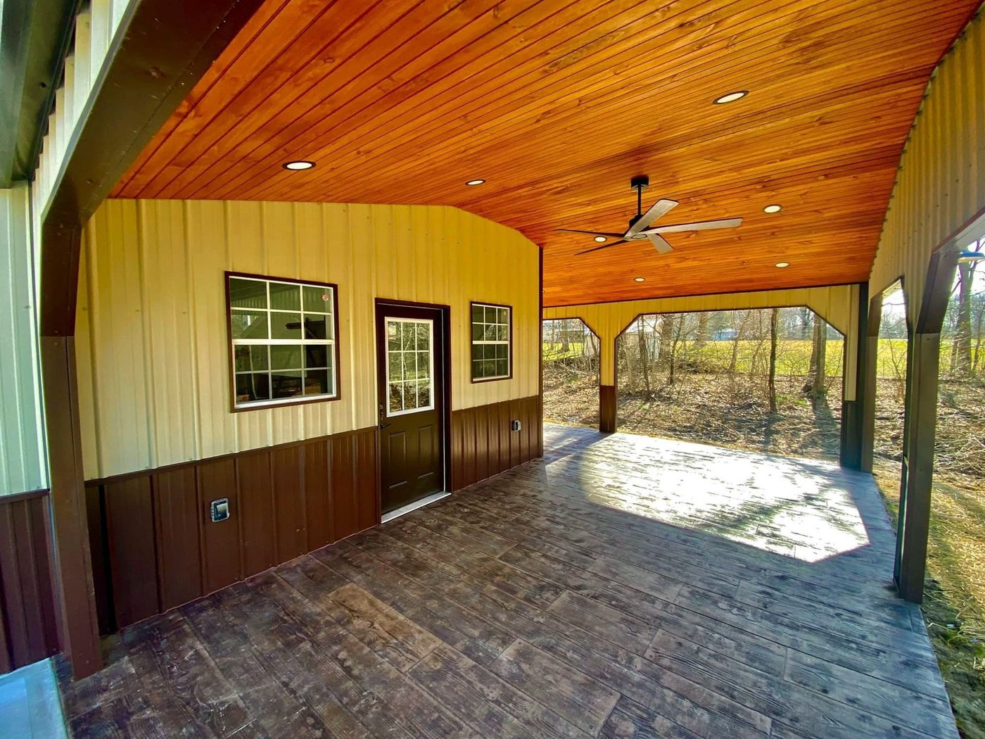 A finished porch with a stained ceiling and fan