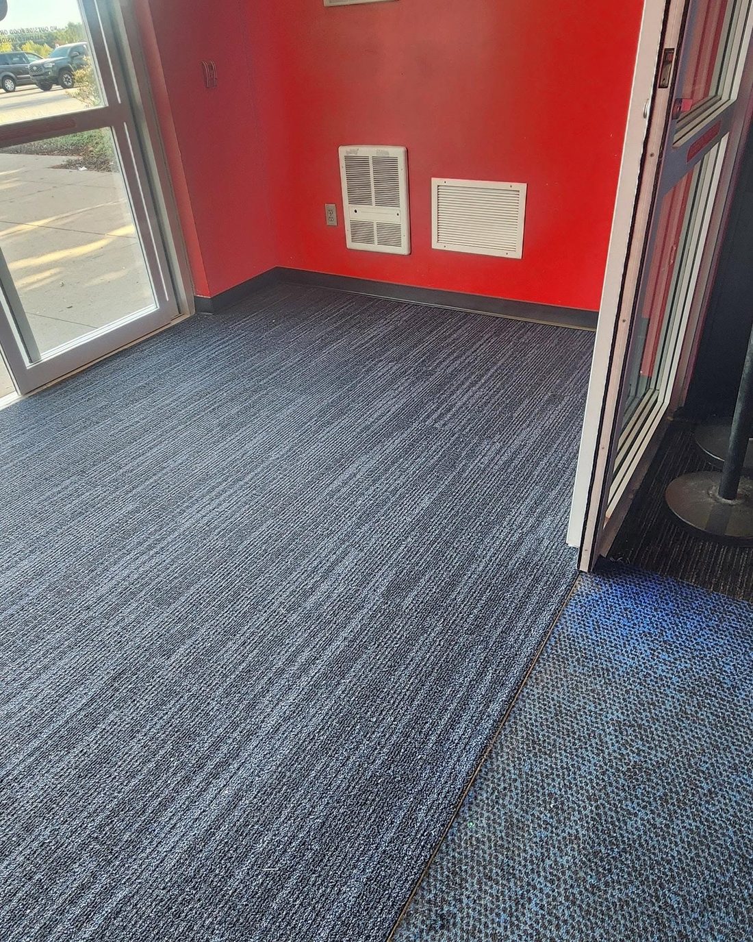 A red-walled commercial room in blue-grey carpet tile