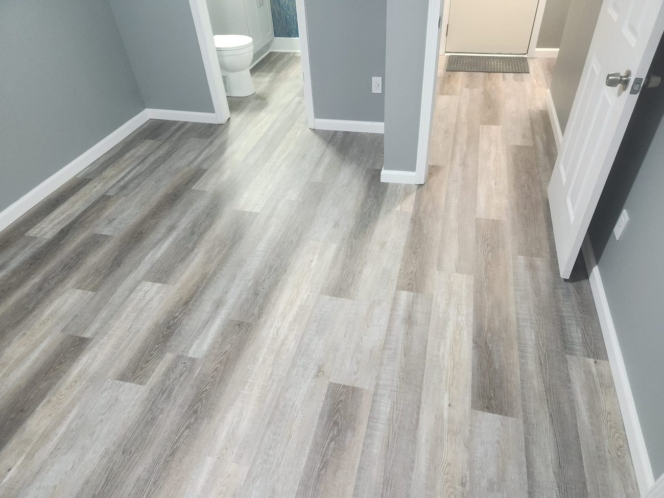 A grey plank hallway leading to bedrooms and a bath
