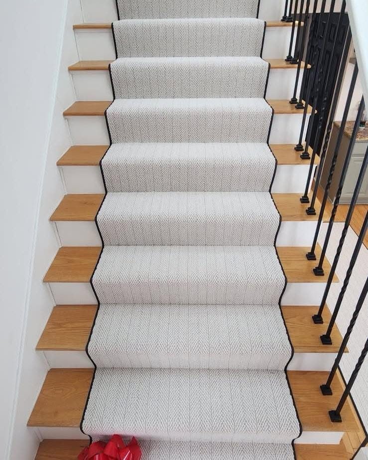 An ivory bound runner down oak stairs with black spindles