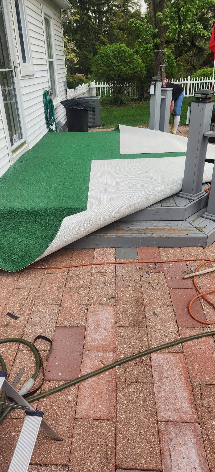 Green turf being laid over a porch and brick patio