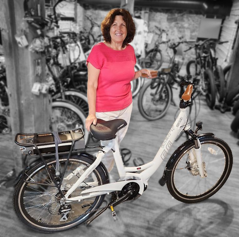 A rider standing over a white step-thru e-bike in the shop