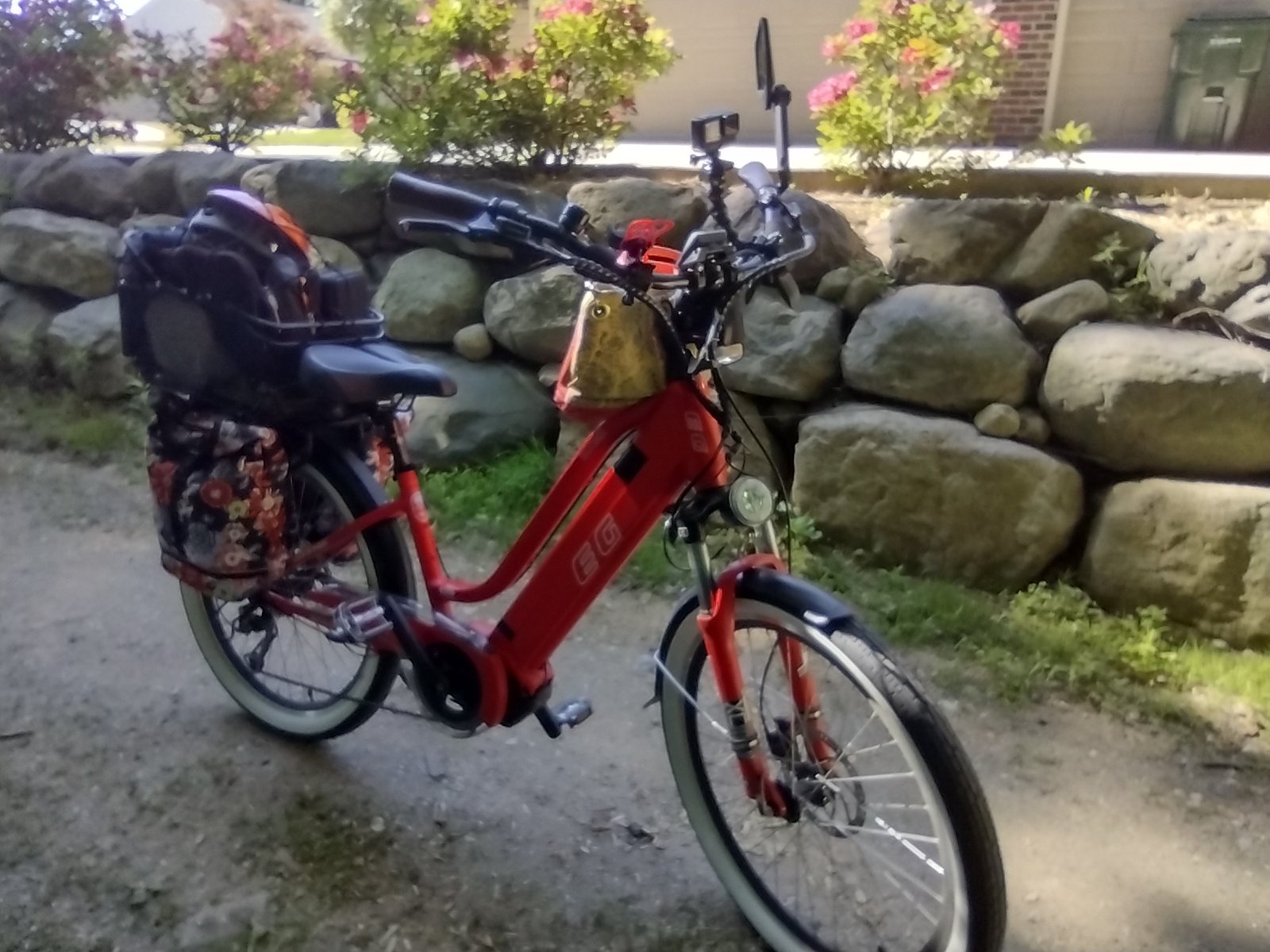 A red e-bike parked beside a stone wall