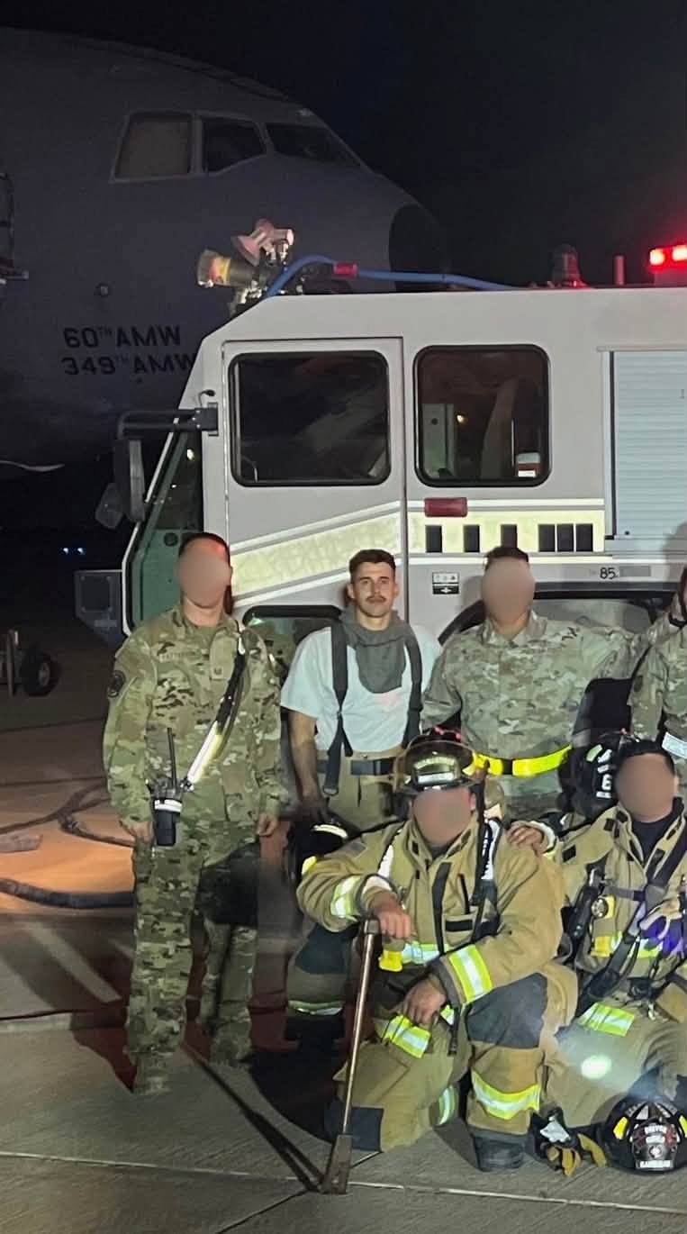 Nick with his Air Force firefighting crew in front of a fire truck and an aircraft