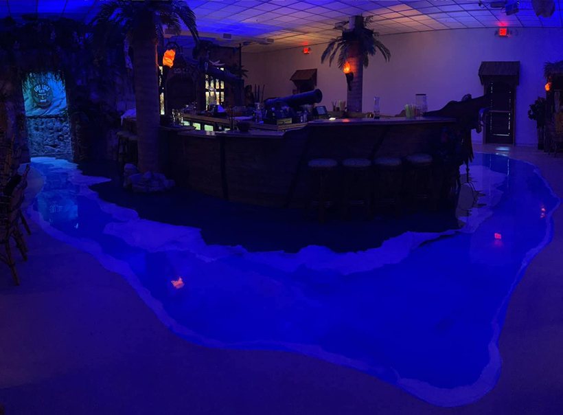 A blue metallic epoxy floor in a bar, under blue light