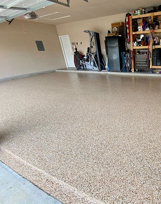 A garage with a tan flake floor
