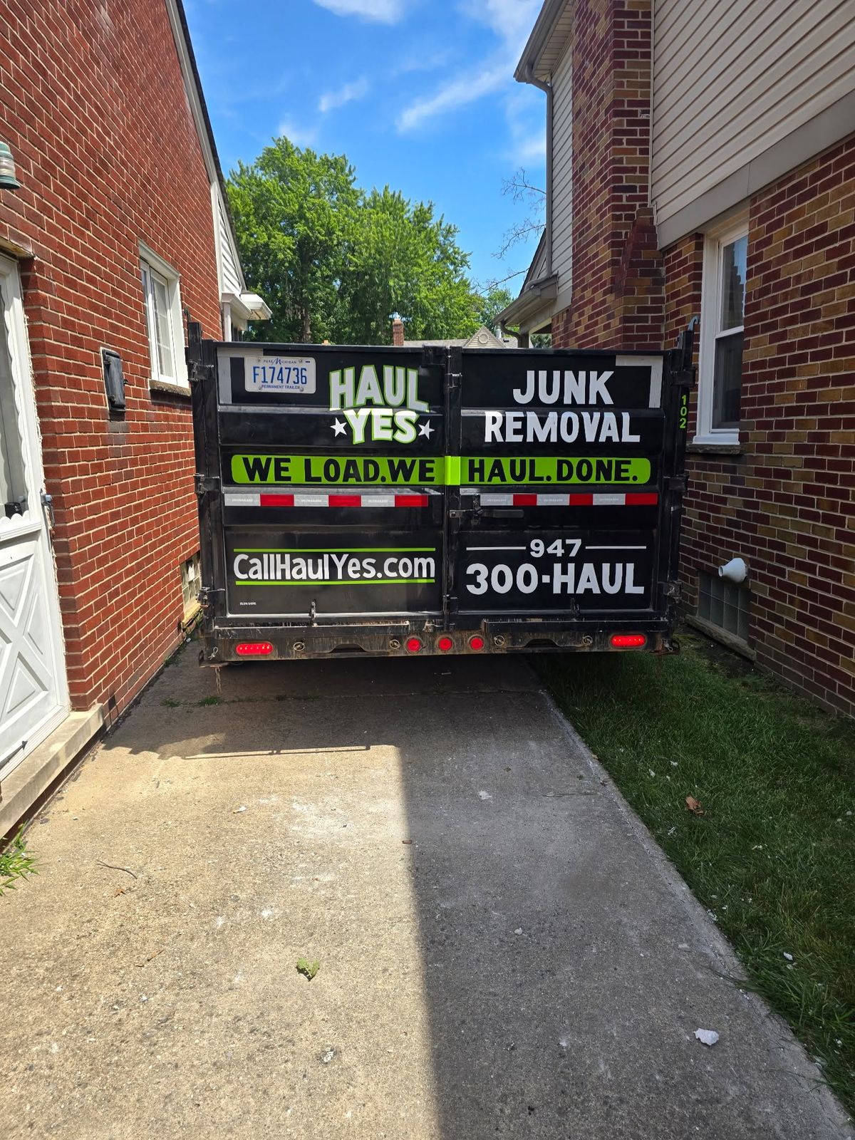 The Haul Yes trailer backed up a narrow driveway between two brick houses