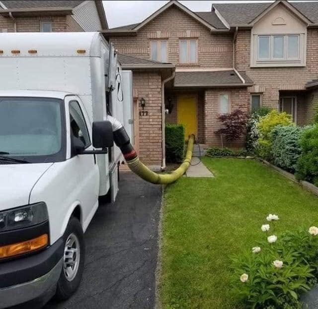 The JJ Duct Cleaning truck with the hose run into a customer's home