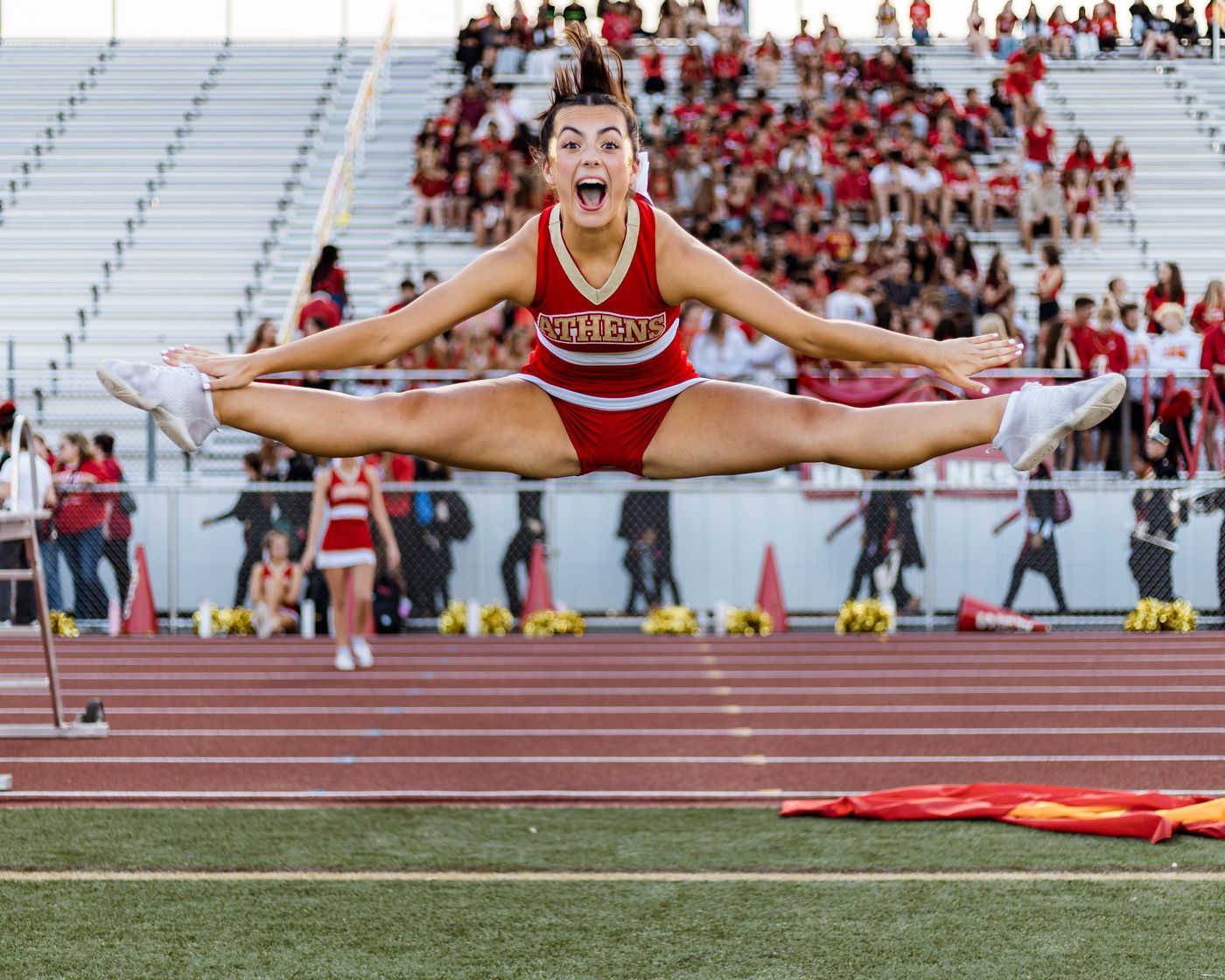 A cheerleader in a toe touch on the track
