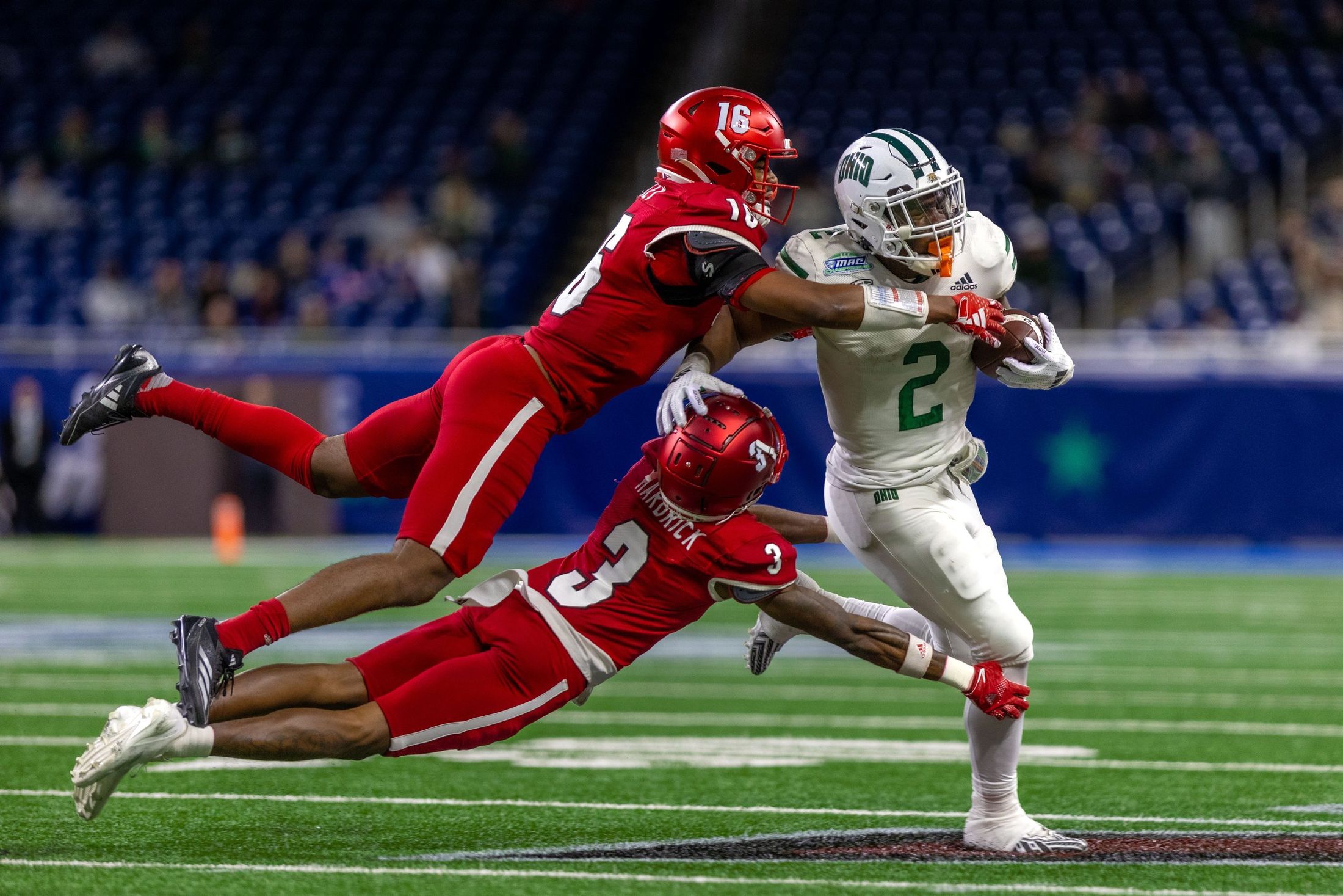A football player breaking two tackles under the lights