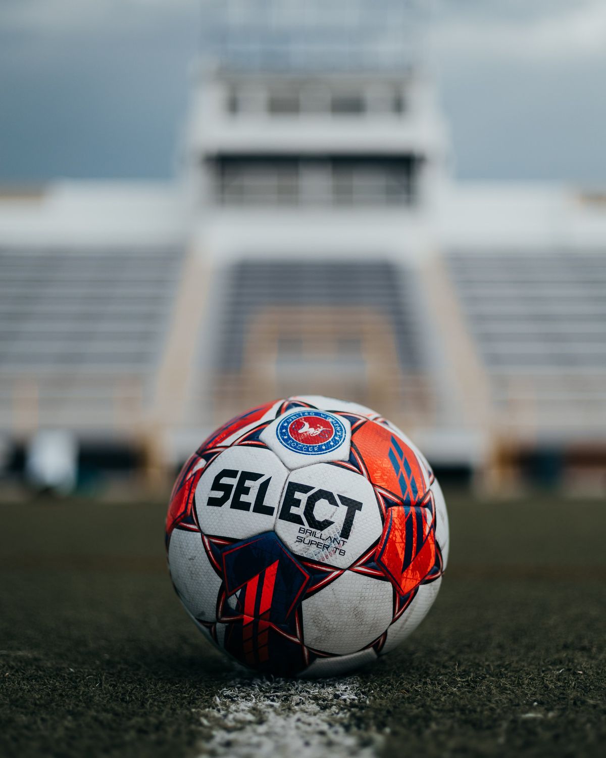 A soccer ball on the line of an empty stadium