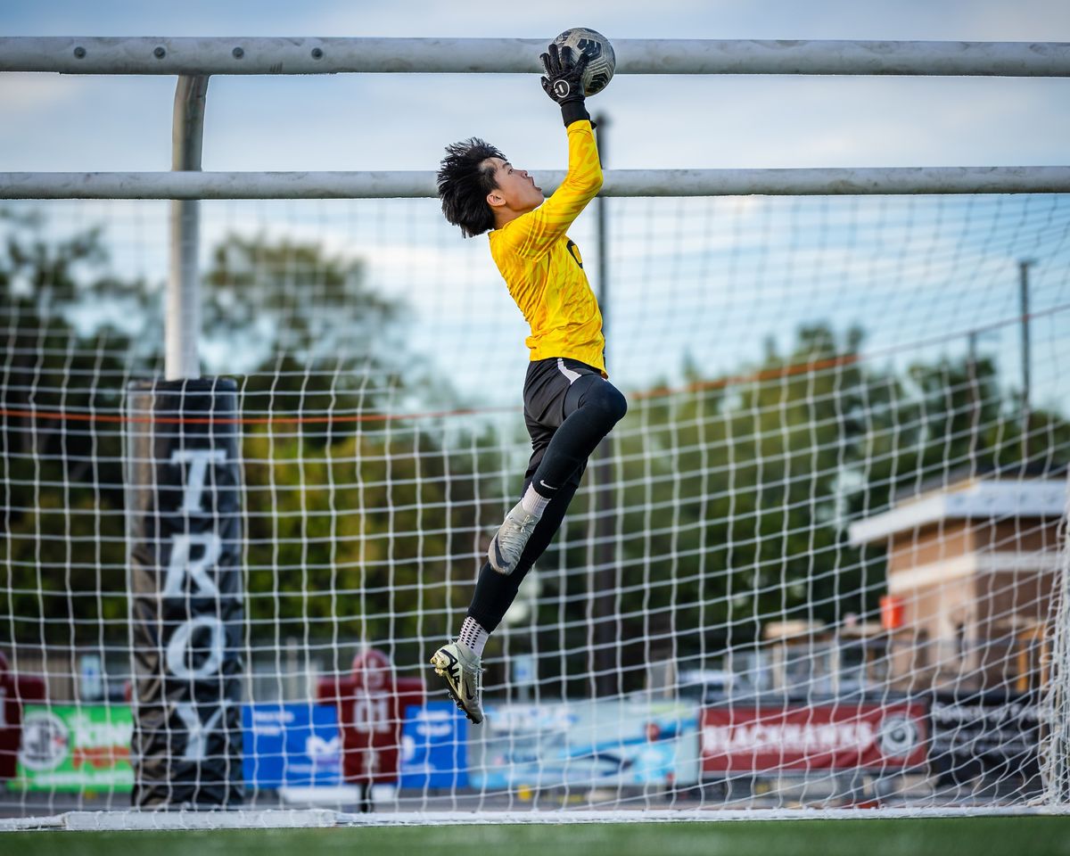 A goalkeeper at full stretch over the bar