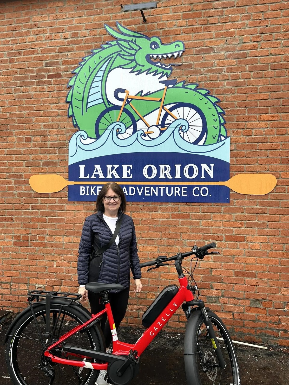 A rider with a red e-bike under the shop's dragon sign