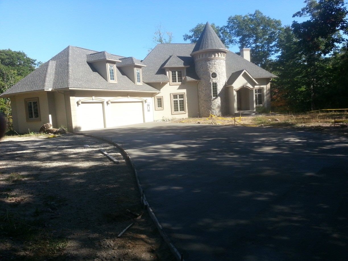 A long new driveway to a stone home with a turret