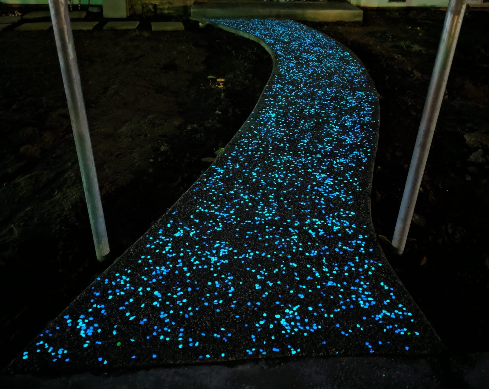 A curved path with glowing stones in its surface, photographed at night