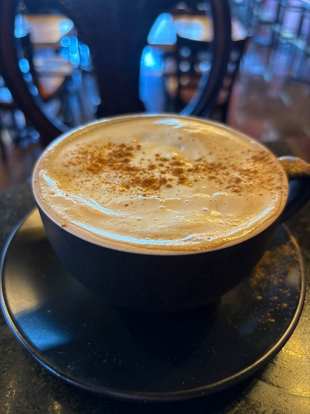 A cappuccino dusted with cinnamon in a black cup