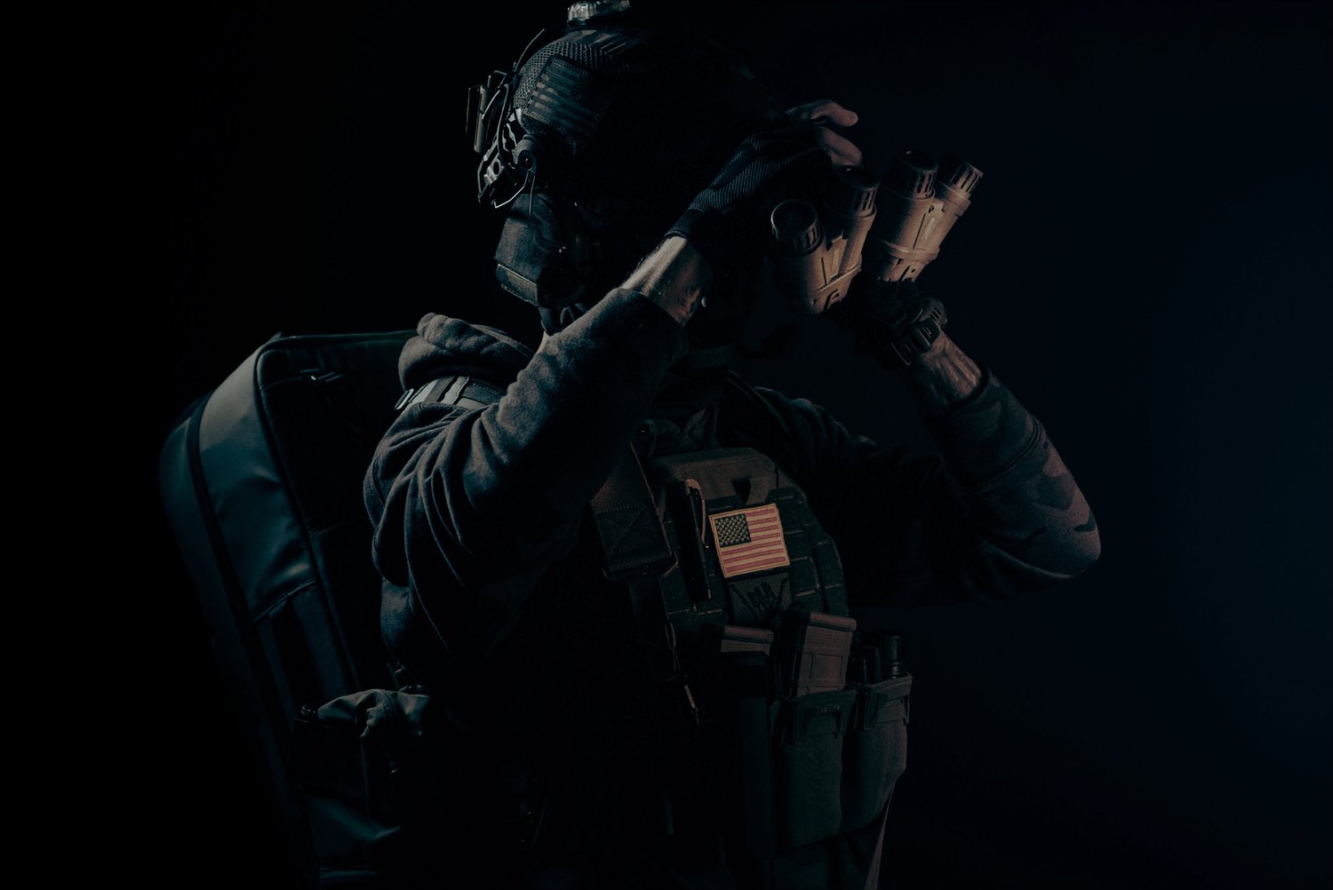 A figure in near-total darkness, hands raised